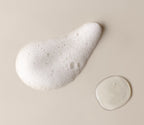A swatch of dense white lather beside a drop of the unlathered gel