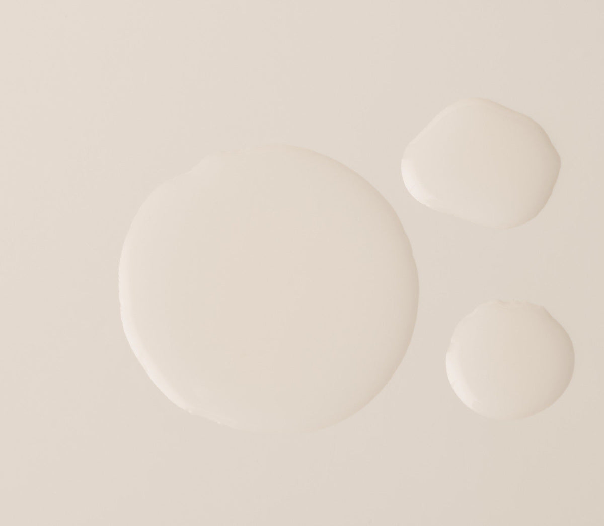 Three droplets of the serum on a flat surface, showing a water-light fluid